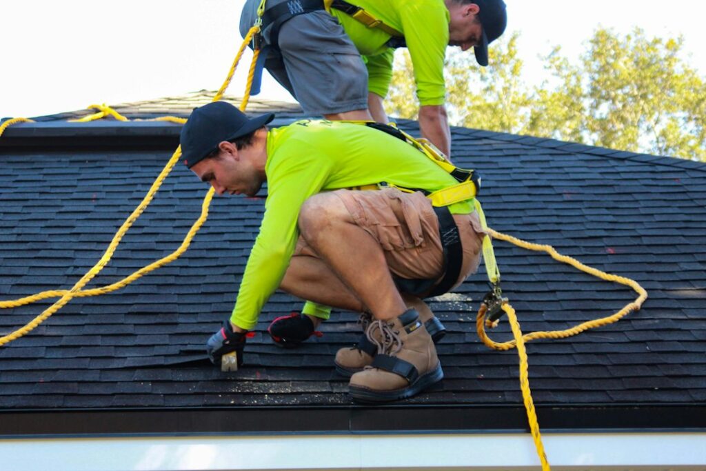 Homeowner reviewing a roofing contract beside storm-damaged shingles and inspection photographs.
